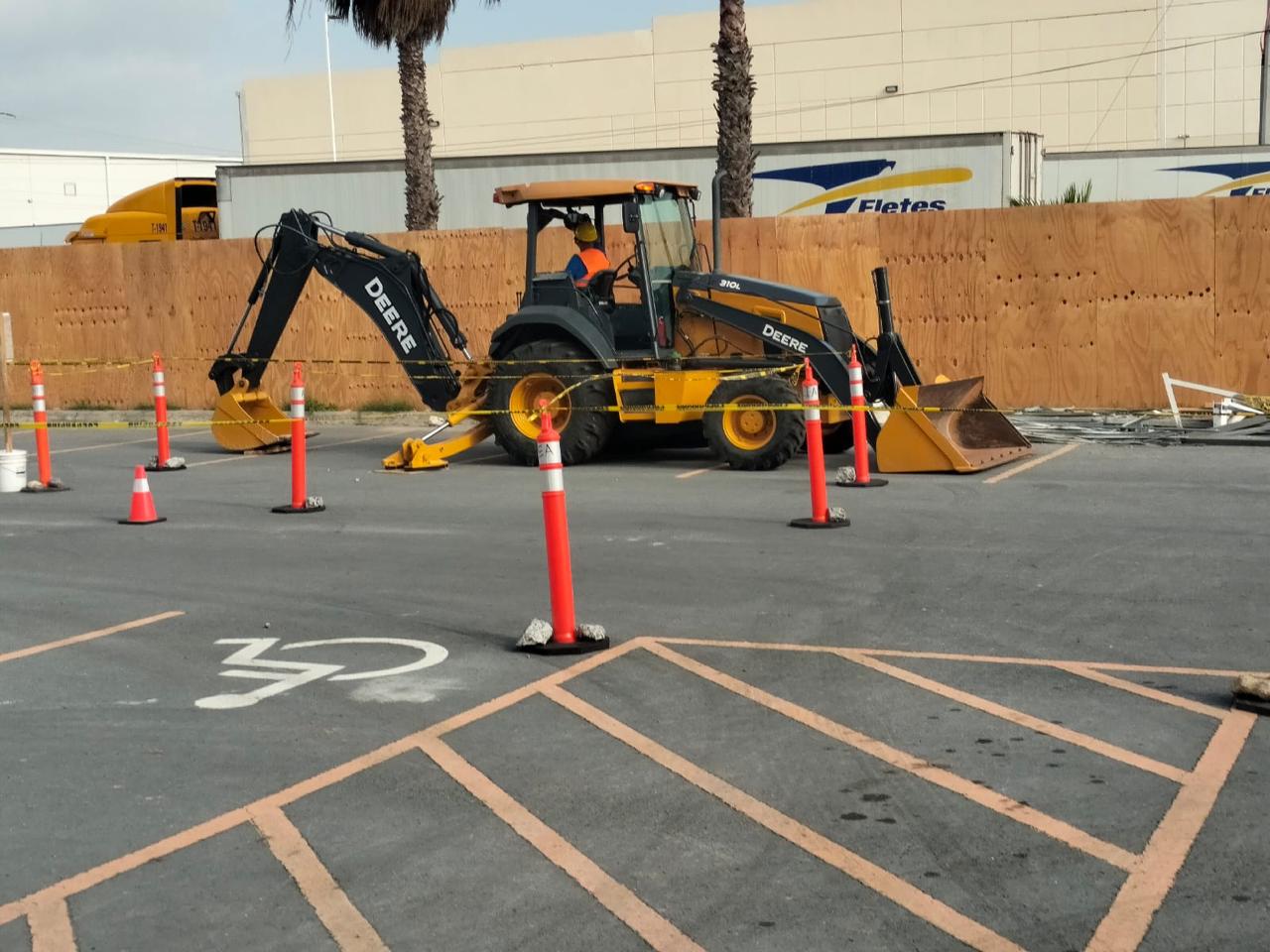 Retroexcavadora en renta trabajando en estacionamiento señalizado de nave industrial en León, Guanajuato