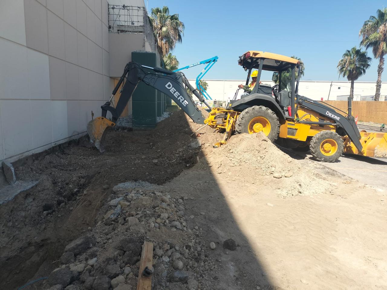Retroexcavadora John Deere 310L excavando cepa para línea de drenaje en obra industrial en León