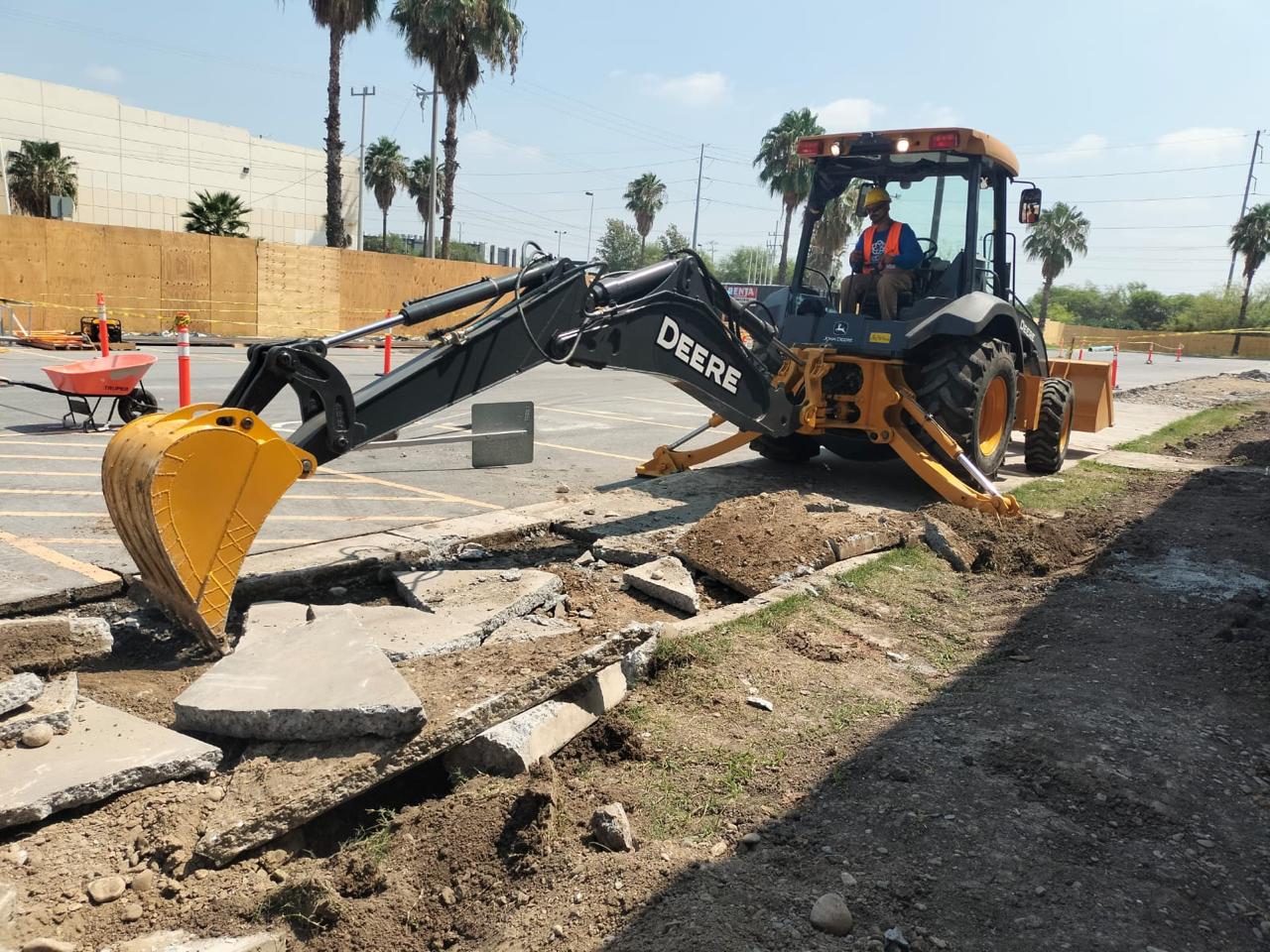 Retroexcavadora en renta retirando losas de banqueta de concreto en obra de urbanización en León, Gto.