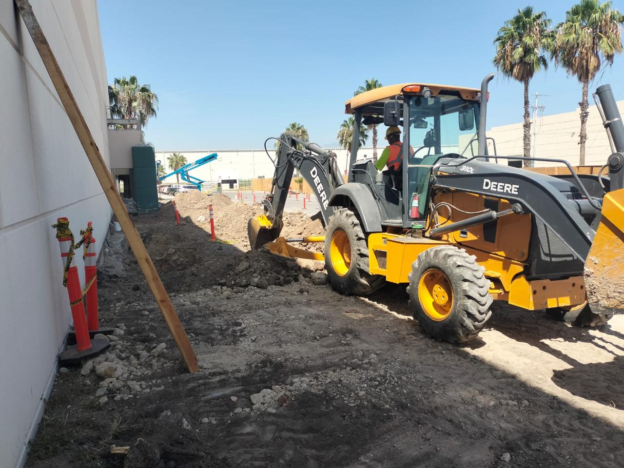 Retroexcavadora 4x4 excavando zanja para drenaje junto a nave industrial en León, Guanajuato
